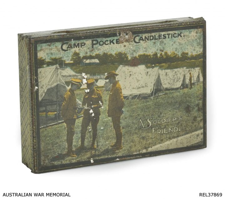 A small Soldiers Friend candlestick tin box with an image of three soldiers standing in front of a line of white tents on the cover