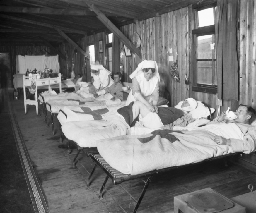 Nurses tending to men in beds injured in battle