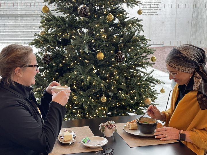 Deux membres du personnel dégustant un repas à la cafétéria du Centre, à côté de son sapin de Noël.