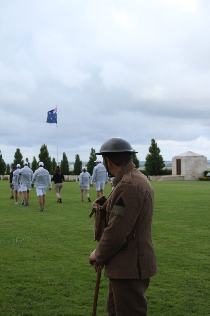 A man wearing the uniform of British soldiers in the First World War facing the cemetery.