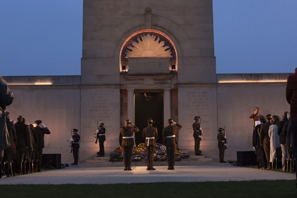 Three Australian soldiers salute the Australian National Memorial before the departure of the guard of the catafalque.