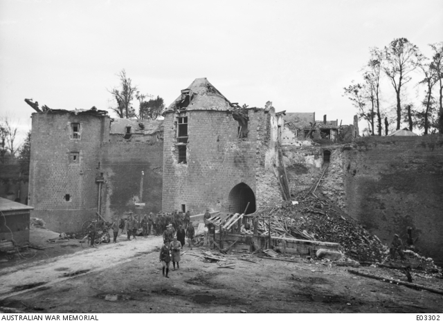 The Right Honourable W. M. Hughes, Prime Minister of Australia, being conducted on a tour of inspection through the ruins of Peronne. The building in the background is the entrance to the Citadel.