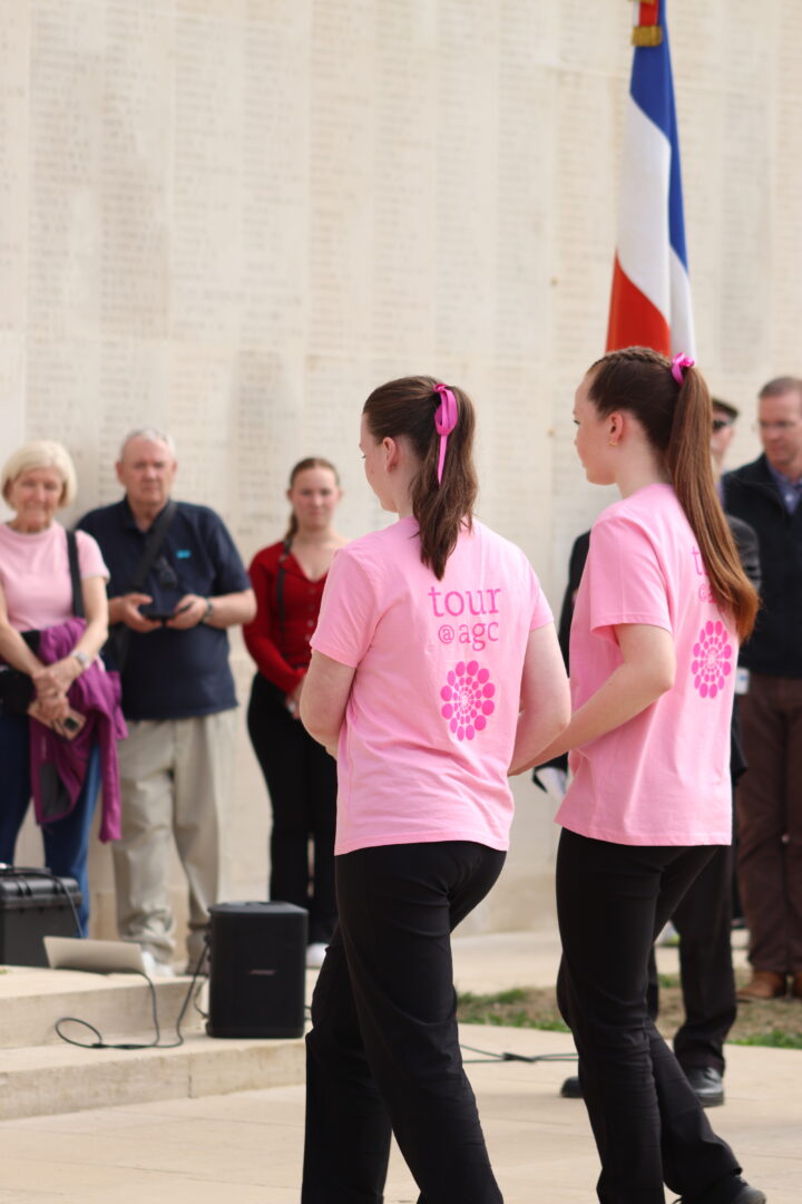 Two choir members laying a poppy wreath at the foot of the memorial